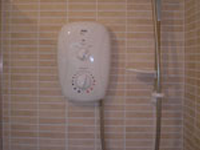 Electric shower attached to beige tiles